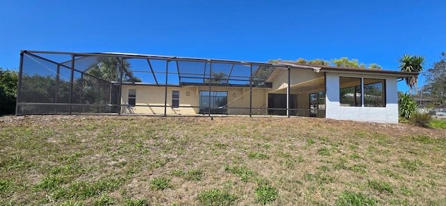 rear view of house featuring a lanai and stucco siding