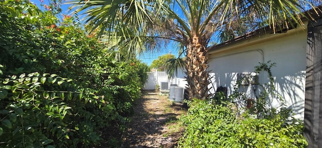 view of side of property with stucco siding, cooling unit, and fence