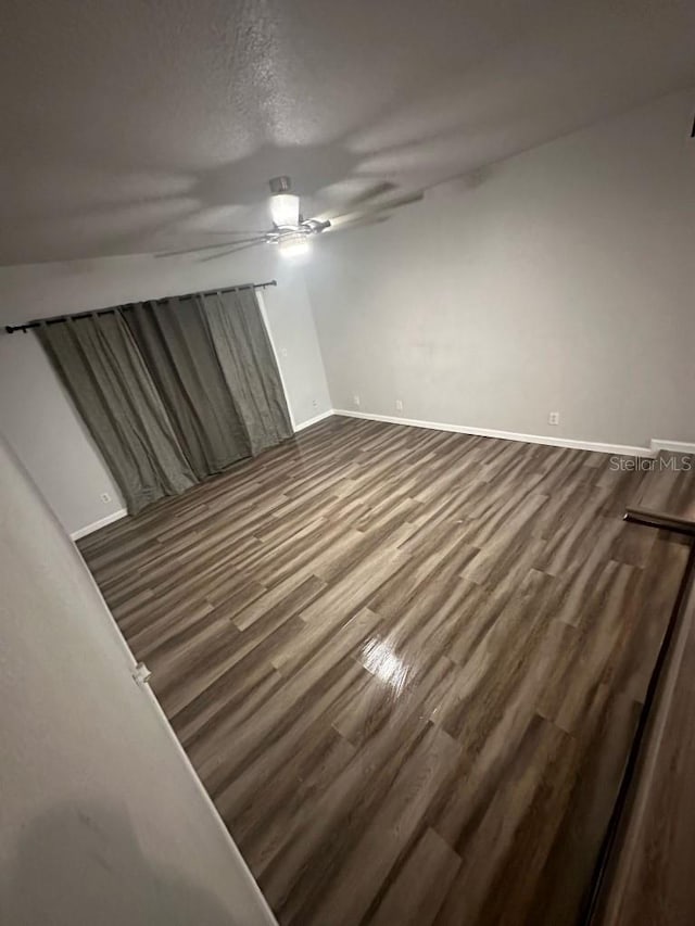 spare room with a ceiling fan, a textured ceiling, baseboards, and wood finished floors