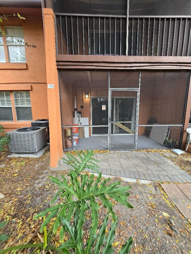 doorway to property with stucco siding and central air condition unit