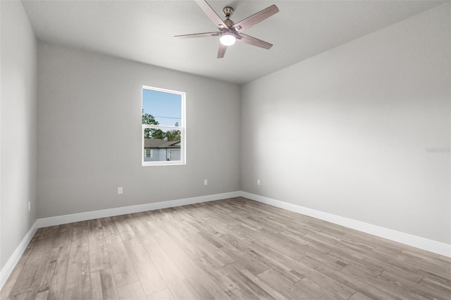 spare room featuring light wood-style flooring, baseboards, and ceiling fan