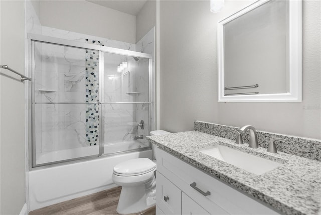 bathroom with enclosed tub / shower combo, toilet, wood finished floors, and vanity