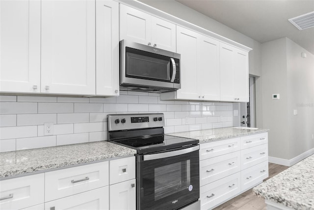 kitchen featuring stainless steel appliances, visible vents, backsplash, light wood-style flooring, and white cabinets