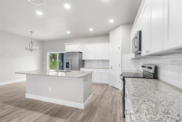 kitchen with a sink, visible vents, white cabinets, appliances with stainless steel finishes, and an island with sink