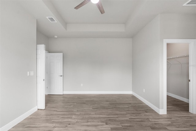 unfurnished bedroom featuring light wood-type flooring, a walk in closet, visible vents, and baseboards