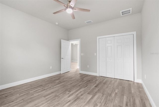 unfurnished bedroom with light wood-style floors, a closet, visible vents, and baseboards