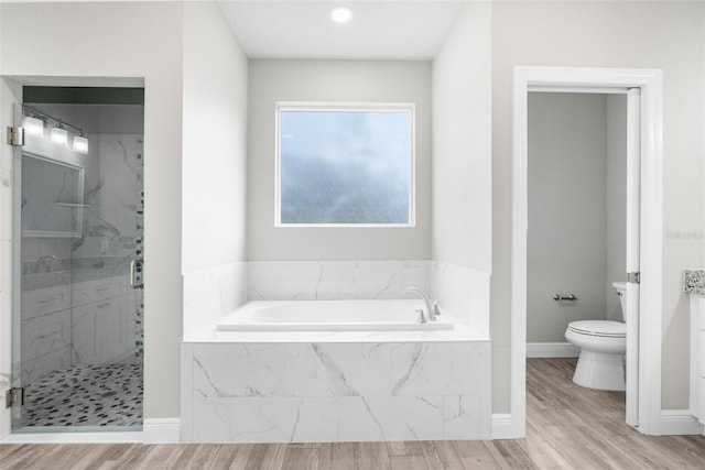 bathroom featuring a garden tub, a shower stall, and wood finished floors