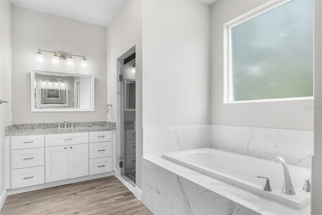 bathroom featuring wood finished floors, a garden tub, vanity, and a shower stall