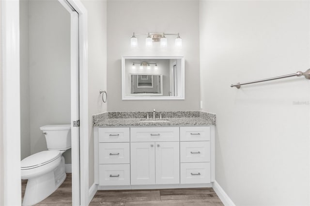 bathroom with vanity, wood finished floors, toilet, and baseboards