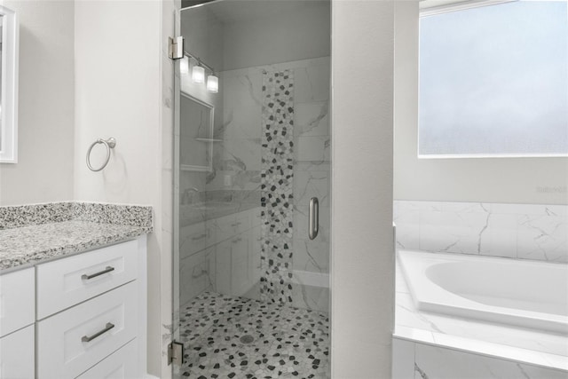 bathroom with a bath, a marble finish shower, and vanity