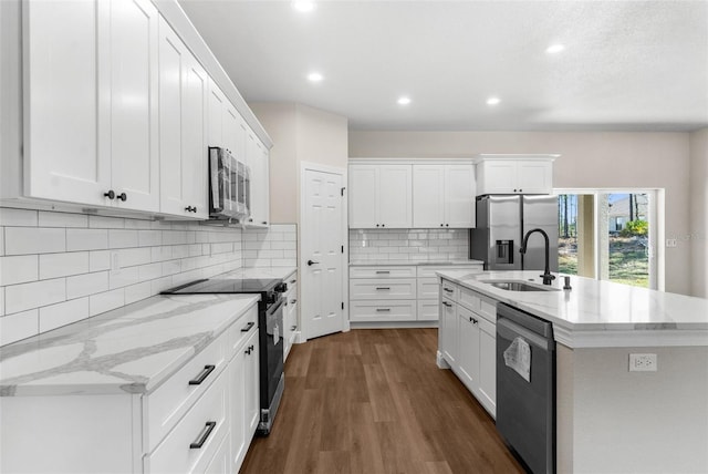 kitchen featuring dark wood-type flooring, a sink, white cabinetry, appliances with stainless steel finishes, and an island with sink