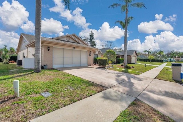 ranch-style house with brick siding, concrete driveway, an attached garage, central AC unit, and a front yard