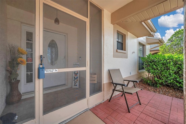 entrance to property featuring a patio area and stucco siding