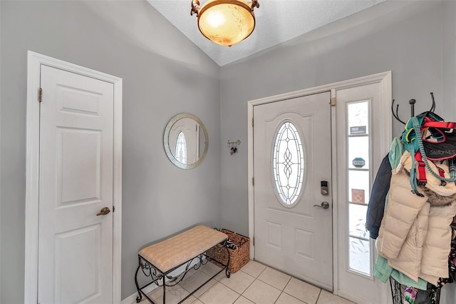 foyer entrance featuring lofted ceiling, a textured ceiling, and light tile patterned flooring