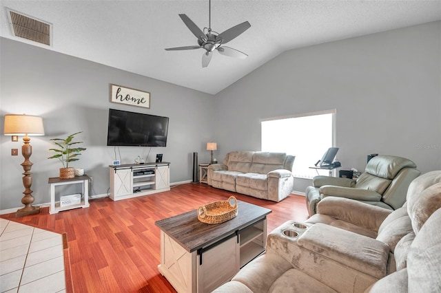 living area featuring visible vents, lofted ceiling, ceiling fan, a textured ceiling, and light wood-type flooring