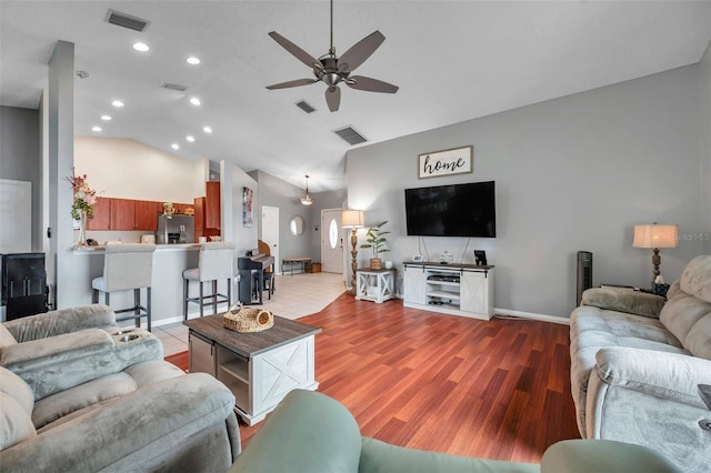 living area with high vaulted ceiling, visible vents, and wood finished floors