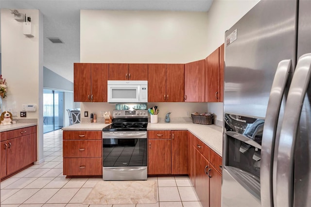 kitchen with light tile patterned floors, a towering ceiling, visible vents, light countertops, and appliances with stainless steel finishes