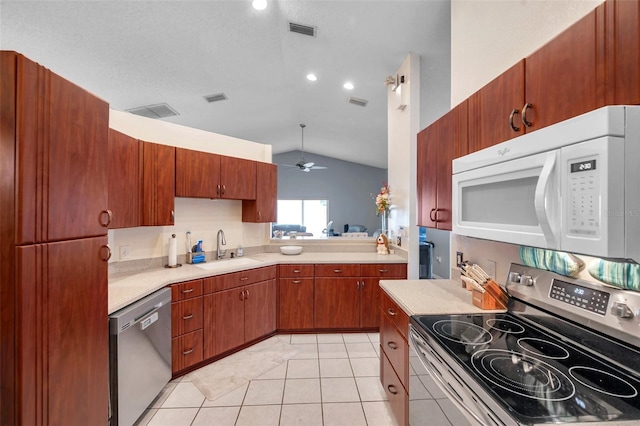 kitchen featuring light tile patterned floors, lofted ceiling, appliances with stainless steel finishes, light countertops, and a sink