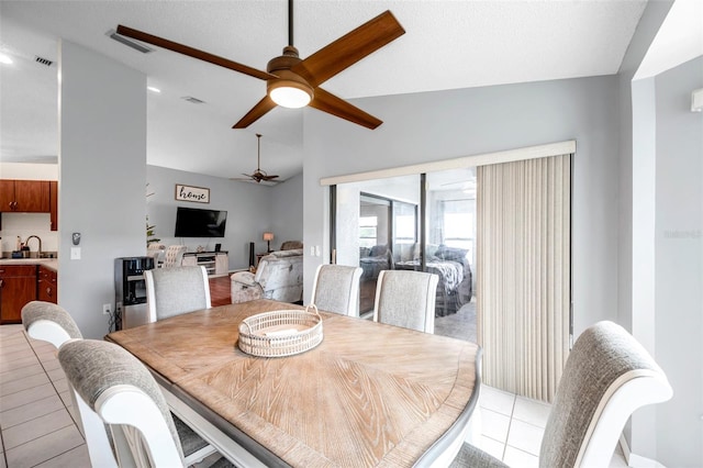 dining room with light tile patterned floors, visible vents, and vaulted ceiling