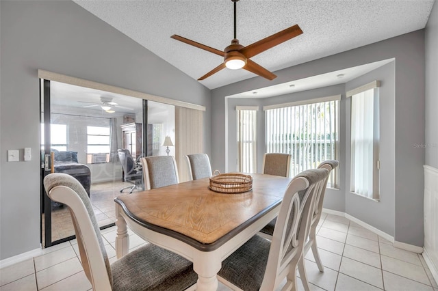 dining space featuring light tile patterned flooring, vaulted ceiling, a textured ceiling, and baseboards