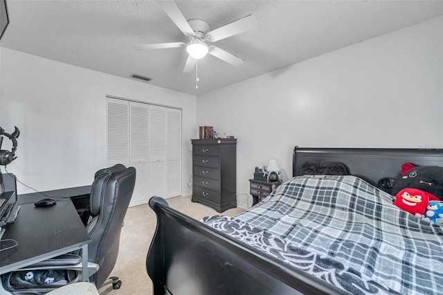 bedroom with light carpet, visible vents, a ceiling fan, a textured ceiling, and a closet