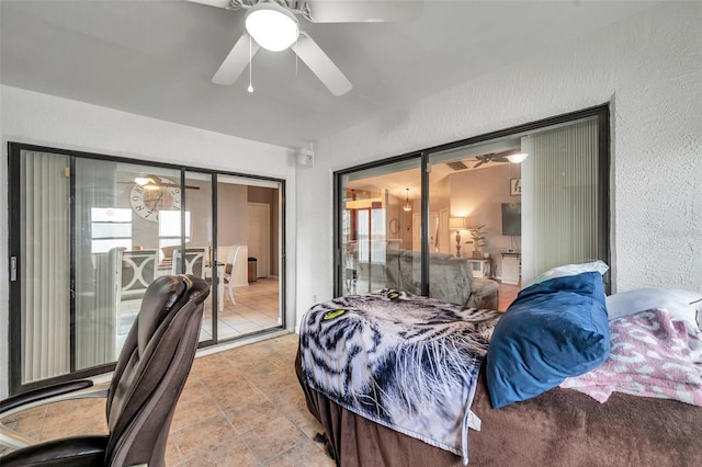 bedroom featuring access to outside, light tile patterned flooring, a ceiling fan, and a textured wall