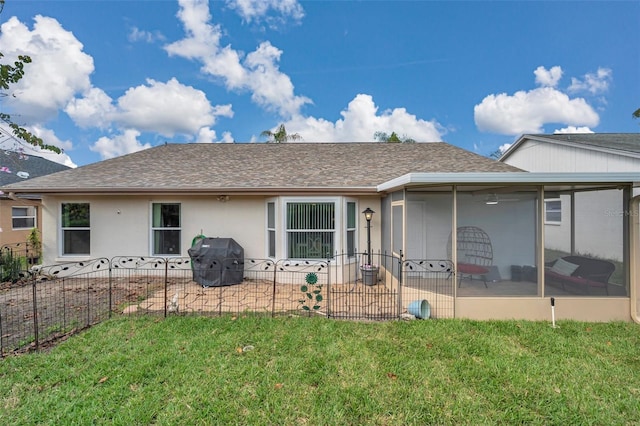 rear view of house featuring roof with shingles, a yard, stucco siding, a sunroom, and fence