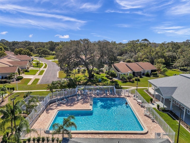 community pool featuring a patio area, fence, and a residential view