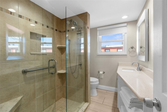 full bathroom featuring toilet, a stall shower, baseboards, and vanity