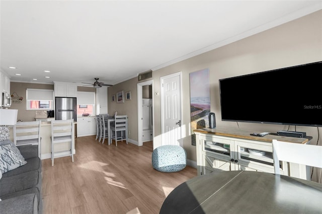 living room featuring baseboards, a ceiling fan, ornamental molding, light wood-type flooring, and recessed lighting