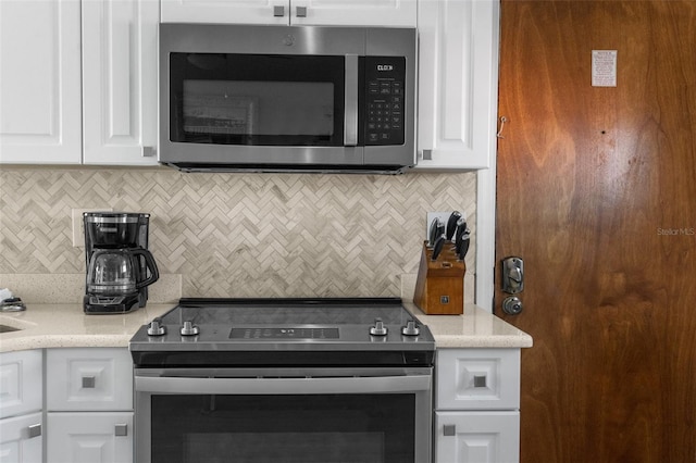 kitchen featuring appliances with stainless steel finishes, backsplash, and white cabinetry