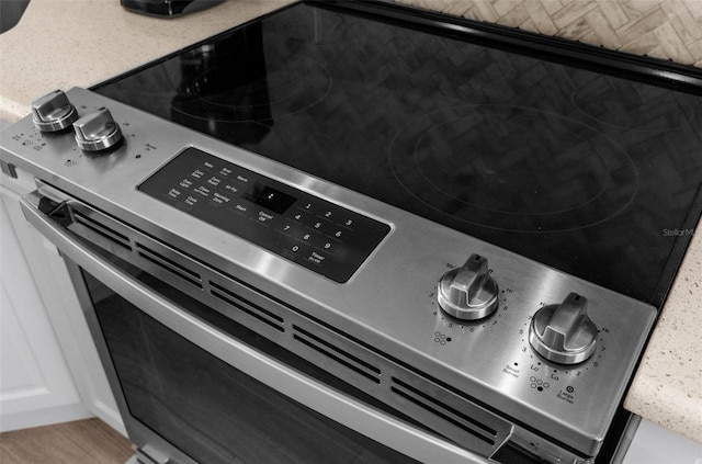 interior details featuring stainless steel range with electric stovetop, light countertops, and white cabinetry