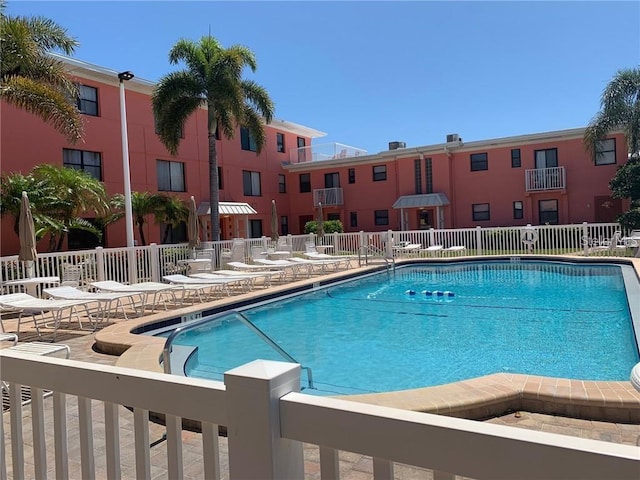 community pool with a patio and fence