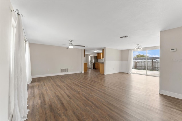 unfurnished living room featuring baseboards, ceiling fan, visible vents, and dark wood-type flooring