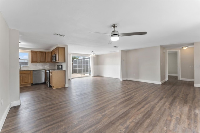 unfurnished living room featuring dark wood-style floors, plenty of natural light, visible vents, and a ceiling fan