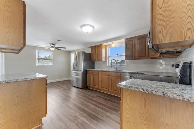 kitchen with stainless steel appliances, a healthy amount of sunlight, a sink, and dark wood-type flooring