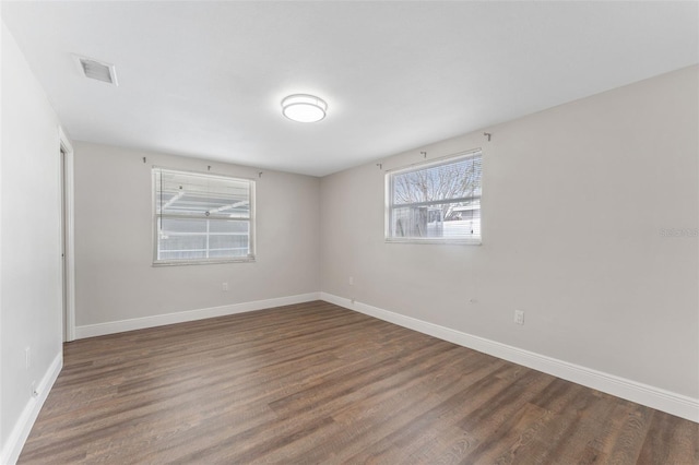 spare room featuring visible vents, dark wood finished floors, and baseboards