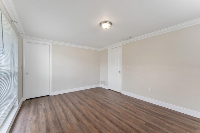 spare room with dark wood-style floors, baseboards, visible vents, and crown molding