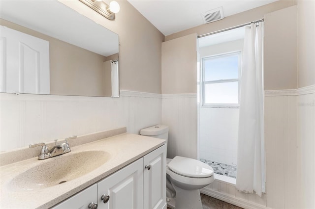 bathroom featuring visible vents, wainscoting, toilet, vanity, and a shower stall