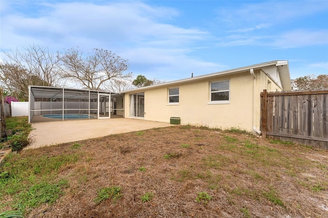 rear view of property with a lanai, stucco siding, a fenced backyard, and a patio