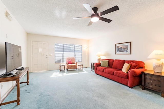 living area with light carpet, ceiling fan, and a textured ceiling