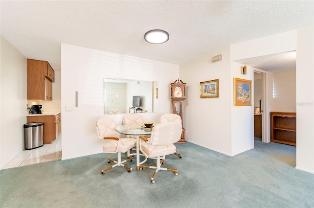 dining area with light carpet, visible vents, and a textured ceiling