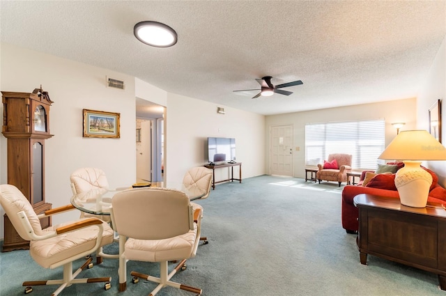 living area featuring light carpet, ceiling fan, visible vents, and a textured ceiling