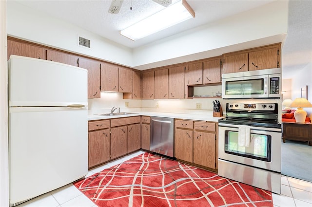 kitchen with visible vents, appliances with stainless steel finishes, brown cabinets, light countertops, and a sink