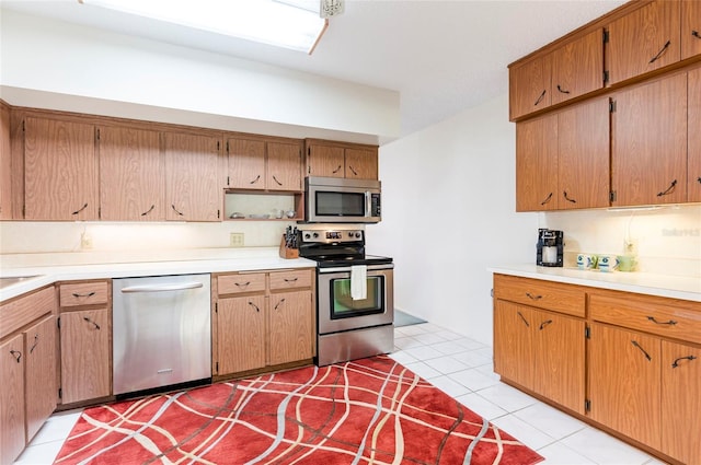 kitchen featuring brown cabinets, light tile patterned floors, appliances with stainless steel finishes, and light countertops