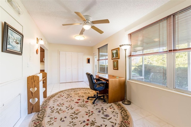 home office featuring a textured ceiling, light tile patterned flooring, visible vents, and a ceiling fan