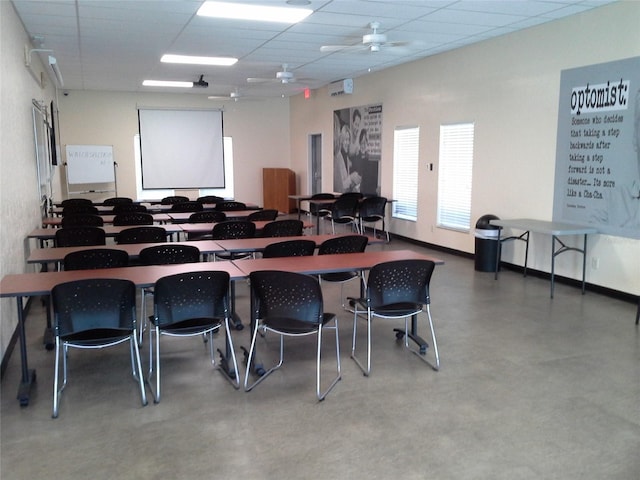 interior space with a paneled ceiling, finished concrete flooring, baseboards, and a ceiling fan