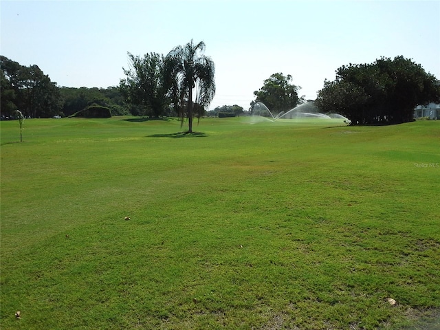 view of property's community with golf course view and a lawn