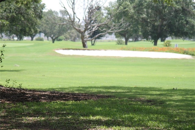 surrounding community featuring view of golf course and a yard