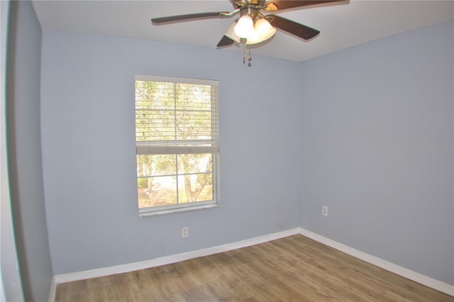 empty room featuring a healthy amount of sunlight, baseboards, and wood finished floors